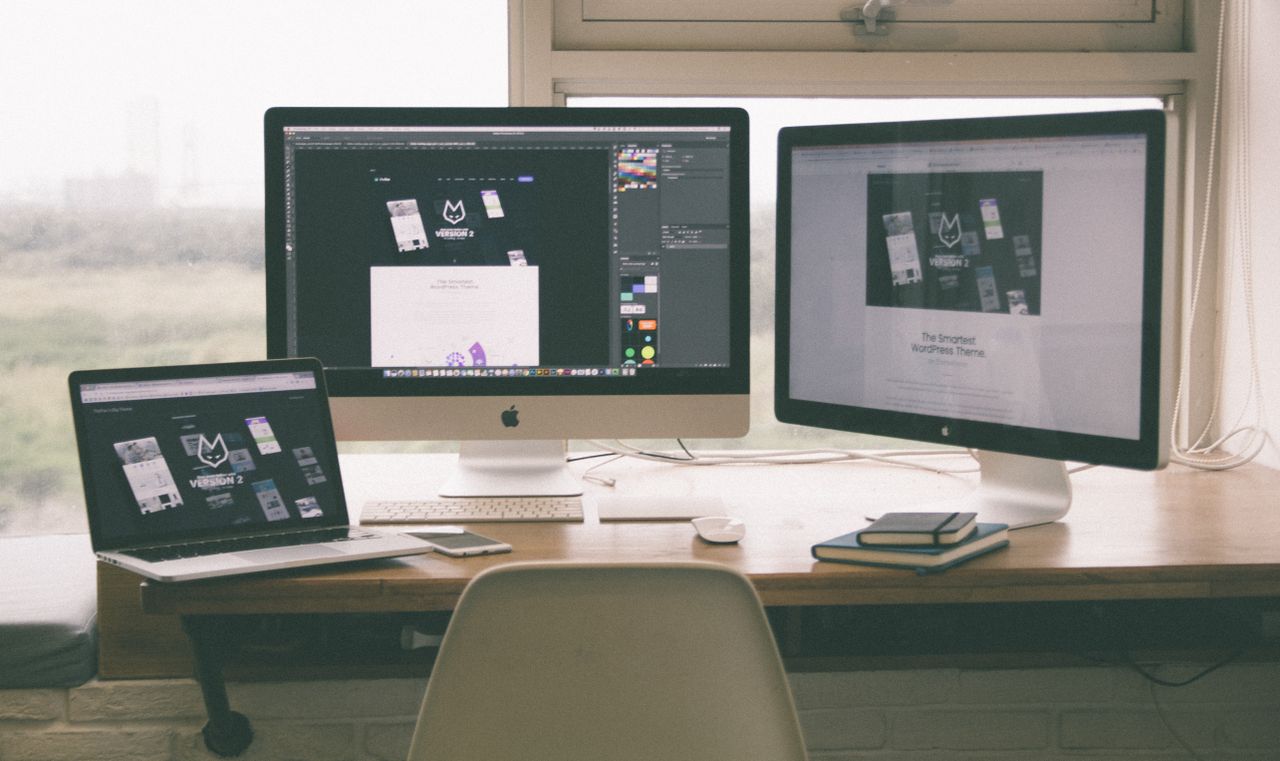 creative Stylish and efficient workspace with multiple monitors, laptop, and smartphone, showcasing a web design project.